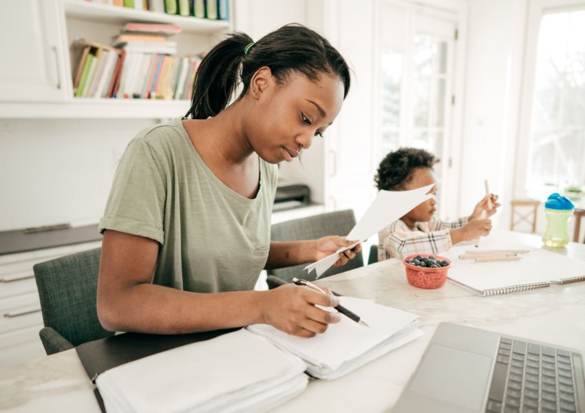 person-writing-on-paper-with-child-behind