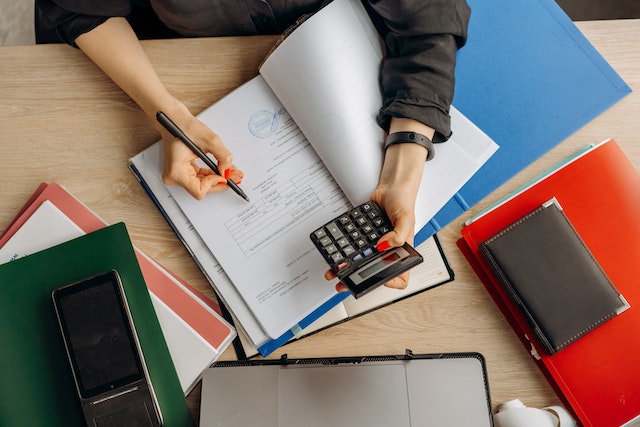 person with calculator writing in a notebook